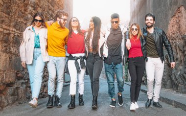 Şehir merkezinde yürürken gülümseyen ve el ele tutuşan neşeli çok ırklı insanlar topluluğu. Arkadaşlık ve birliktelik gençlerin yaşam tarzı konsepti.