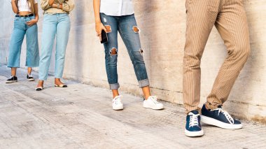 Sıraya dizilmiş insanlarla arasına sosyal mesafe koyma kavramı. Tanınmayan yüzler, Coronavirus salgınına karşı yasalara saygılı gençlerin ayaklarına yakın çekim..