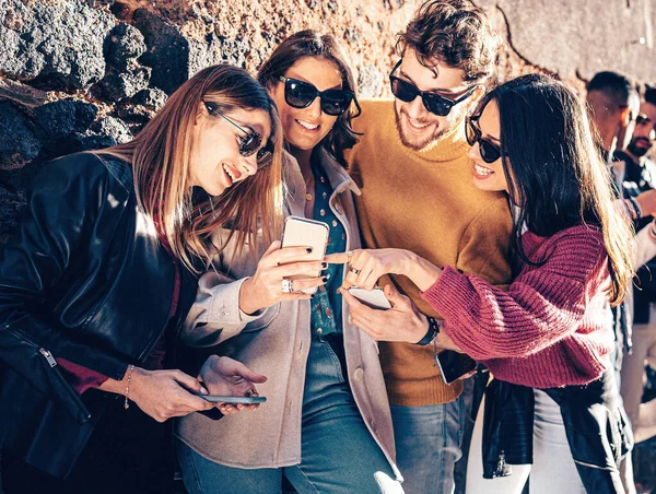 İnternette sörf yapan bir grup genç açık havada oturup sosyal ağ içeriğini izliyor..