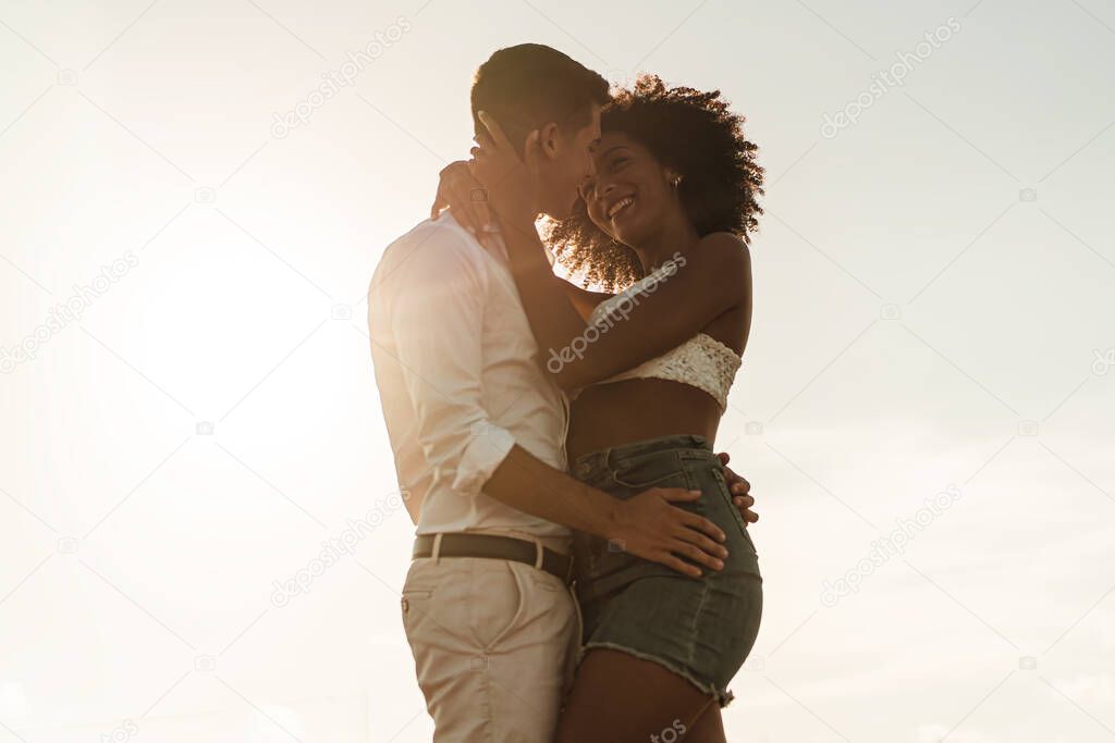 Multiracial young couple kiss. Caucasian guy holding his Afro American woman in his arms. Romance and integration lifestyle concept.
