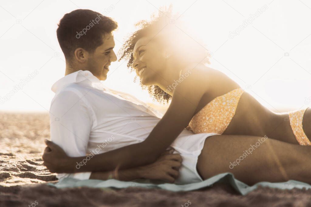 Interracial couple kissing on the beach in the summer