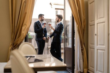 Genç işadamı otel odasının balkonunda birlikte kırmızı şarap içmeyi tartışıyor..