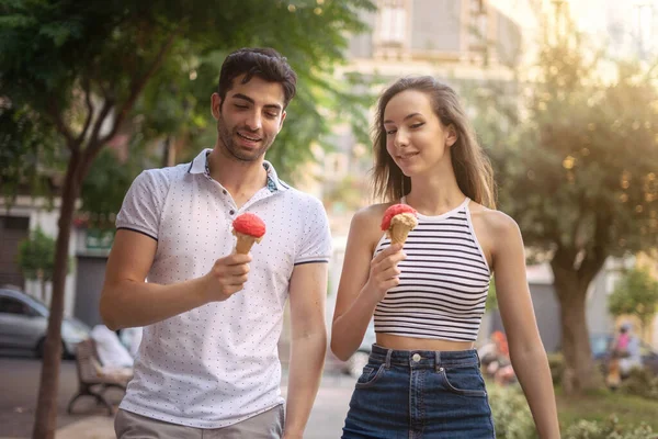 Sokakta yürüyen ve dondurma yiyen bir çift mutlu genç.