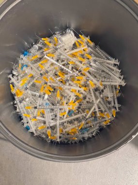 Coronavirus aşısı için kullanılan şırıngalarla dolu bir çöp kutusu. Covid-19 Aşılama Konsepti.