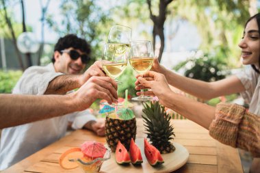 Bir grup genç arkadaş terasta toplanıp kadeh kaldırarak beyaz şarap kadehlerini tokuşturarak eğleniyorlar.