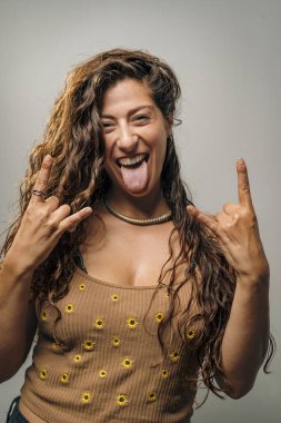 Vahşi bukleler ve kendine güvenen bir gülümsemeyle genç bir kadın, parlak bir stüdyoda cesurca rock and roll hareketleri sergiliyor. Onun oyuncu tavırları sahneye enerji katıyor..