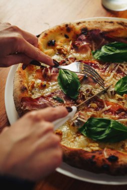 Üzerinde domuz eti, peynir, sebze ve sebzeler olan iki gurme pizza, açık kutularda, ahşap bir masada köpüklü bir içecek, tepeden bakıldığında..