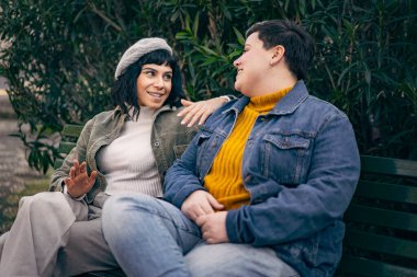 Parktaki bankta oturan, konuşan, gülen ve rahatlayan iki genç kadın..