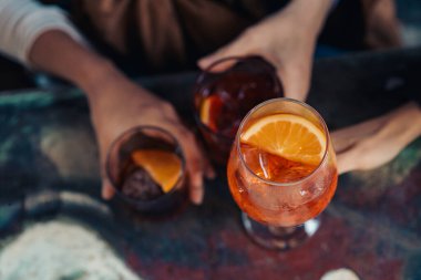 Masanın üzerinde kokteyllerin düz manzarası vardı. Rahat bir dostluk anında içkiye uzanan eller ve bir şehir kafesinde paylaşım..
