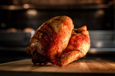Profesyonel bir fırının içindeki ahşap bir tahtanın üzerinde gevrek altın ciltli kızarmış tavuk. Restoran, yemek ve yemek hazırlama konsepti.