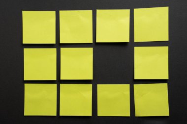 Koyu arkaplan üzerinde bir ızgara içinde düzenlenmiş boş sarı yapışkan notlar, planlama, organizasyon, iş akışı yapısı ve kopyalama alanı temsil eder.