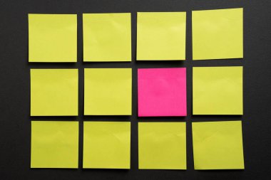 Sarı banknotlardan oluşan bir ızgaranın içine yerleştirilmiş pembe yapışkan not, fark, öncelik ve gruptan ayrılmayı temsil ediyor..