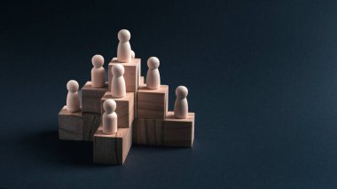 Kavramsal görüntü, tahtadan bir piramidin içinde karanlık bir yüzeye karşı dizilmiş tahta figürleri gösteriyor. Kurumsal hiyerarşiyi, liderlik yapısını, takım desteğini ve iş, yönetim, HR ve strat kurumlarında kurumsal planlamayı resmetmeye uygundur