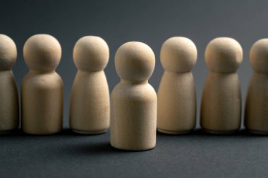 Tek bir ahşap figür, liderliği, bireyselliği ve kalabalıktan ayrı durmayı temsil eden benzer figürlerden oluşan bir grubun önünde duruyor. Etki, karar verme ve başkalarına önderlik etmeyi gösteren asgari iş konsepti