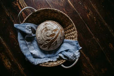 Geleneksel el yapımı, ev yapımı ekşi ekmek sepette, ahşap arka plan, mavi çaydanlık.