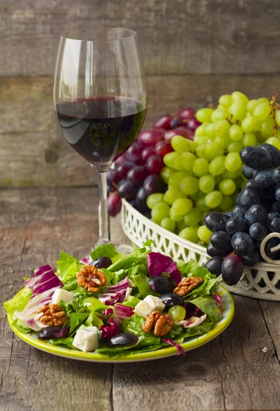 Insalata con uva, erbe aromatiche, noci e formaggio blu e un bicchiere di — Foto Stock