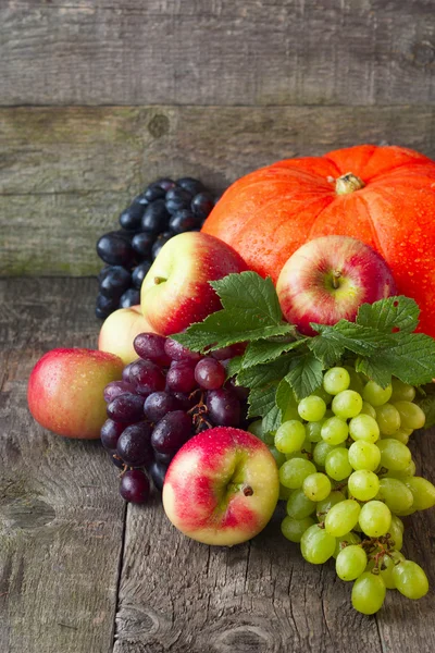 Una zucca, mele, uva su fondo di legno — Foto Stock