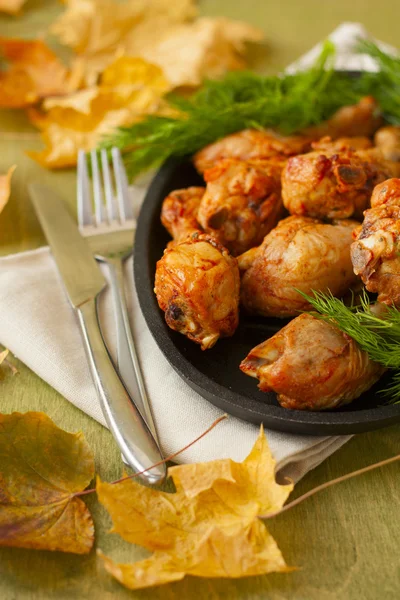 Baked chicken drumsticks and fresh dill on a wooden background — Stock Photo, Image