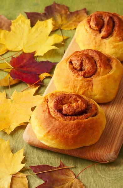 Rotoli di zucca cannella su uno sfondo di foglie di autunno — Foto Stock