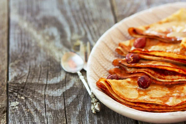 Pancake di piring dengan saus karamel dan kacang di punggung kayu — Stok Foto