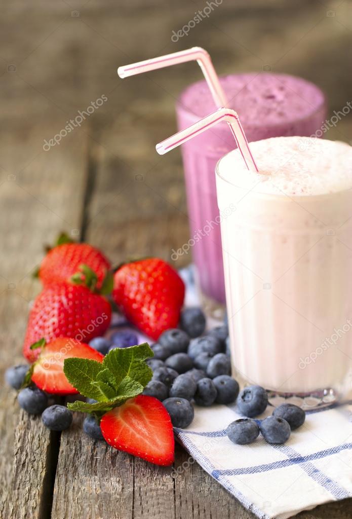  milk shakes and fresh berries on a dark wooden background