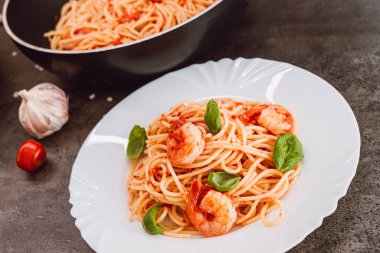 Domates soslu spagetti, fesleğen ve karides. İtalyan mutfağı. Taze, sağlıklı, ana yemek, tabakta servis ediliyor.