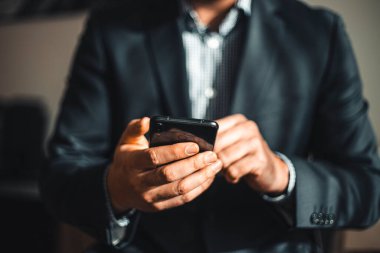 Cep telefonuyla el görüntüsünü kapat. Cep telefonunu tutan takım elbiseli bir iş adamı.