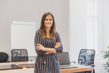 Stylich çekici genç bayan ofiste. Kollarını kavuşturup masada duran iş kadını.