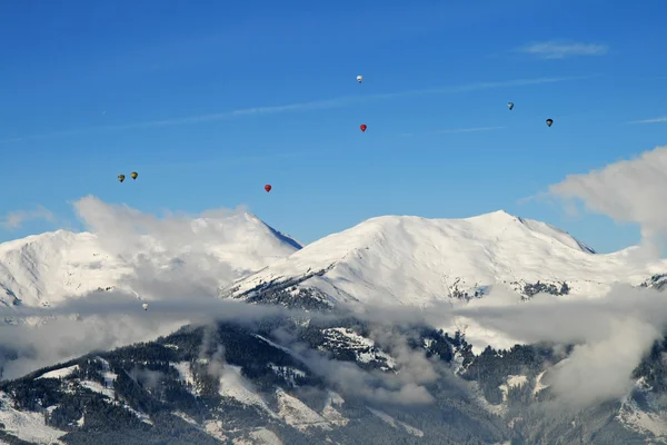 Hot air ballooning over the tops of snowy mountains — Stock Photo, Image