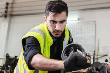 Mühendisler metal parçaları üretmek için makinenin üretimini kontrol ediyorlar. Metal metal torna ile metal parçaları üreten bir işçi..