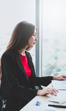 Genç bir iş kadını ofiste oturup ciddi ciddi düşünüyor ve beyaz bilgisayar üzerinde çalışıyor..