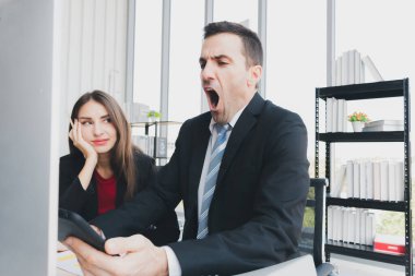 Ofiste çalışırken elinde akıllı telefon tutan bir işadamı. Patron güzel bir ofis çalışanı ile çalışırken uykulu..