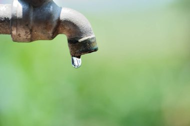 Bulanık arkaplanda eski musluğu ve su damlasını kapat