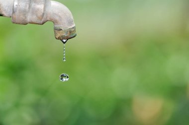 Bulanık arkaplanda eski musluğu ve su damlasını kapat