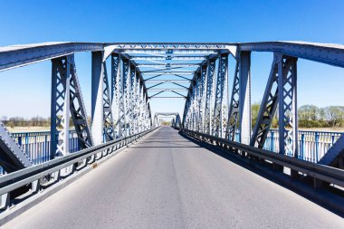 Metal köprü arka planı. Köprü inşaatı. Boş asfalt yol. Narew nehri üzerinde fırtınalı uzun bir köprü. Polonya 'daki Tykocin köyü.