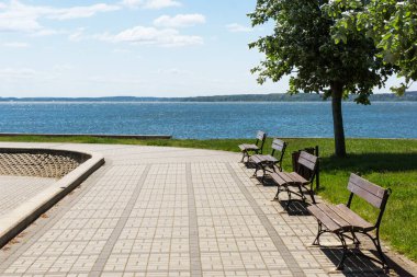 Göl kenarındaki banklarda. Su boyunca yürüme yolu. Polonya 'daki Gizycko şehri. Yeşil çimenlik güneşli gün tatili.