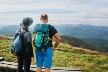 Polonya 'daki Bieszczady Ulusal Parkı. Sonbahar dağ yürüyüşü. Kırsal manzara arka planı. Tepede yürüyüş parkurunda. Manzarayı izleyen turistler. Arkadaşlar yürüyüşlerini planlıyorlar.