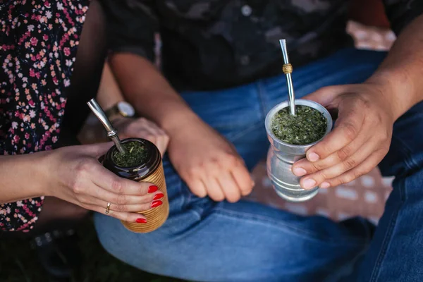 Yerba mate tea in bombilla. Special metal straw. South America popular hot drink. Couple drinking healthy herbal beverage. Engagement outdoor picnic.