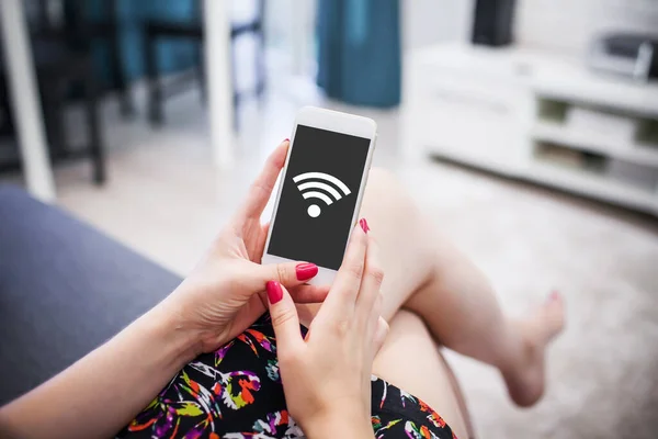 Wi-fi ikonlu akıllı telefonu tutan kadın. Ev arkaplanı. 