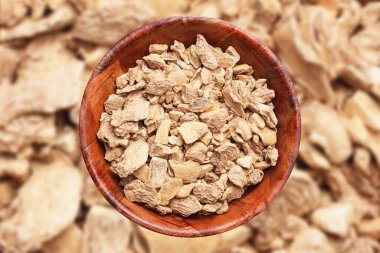 Kızıl arka plan. Tahta kasede zencefil parçaları. Hint baharat dokusu. Boş fotokopi alanı pişirme arka planı. Ginger kök dokusu.