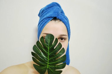 Kafasında havluyla arka planda bir kadın elinde bir palmiye yaprağı tutuyor.