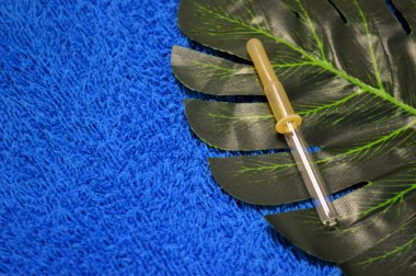 Pipet palmiye yaprağının üzerinde, mavi kumaşın arka planında yatıyor.