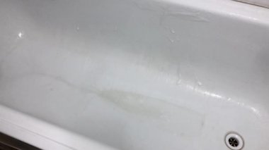 Lastik sarısı bir eldiven banyoyu süngerle yıkar..