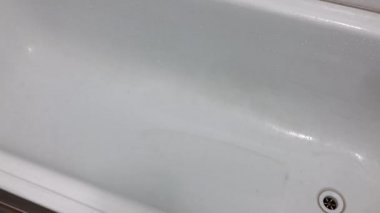 Lastik sarısı bir eldiven banyoyu süngerle yıkar..