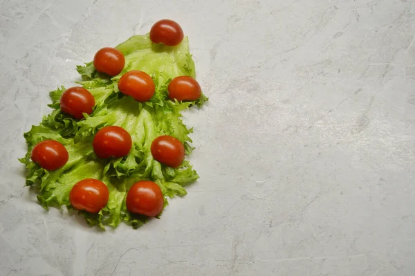 Árvore de Natal feita de alface e tomate em um fundo de madeira leve — Fotografia de Stock