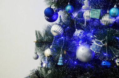 Beyaz arka planda beyaz ve mavi oyuncakları olan Noel ağacı.