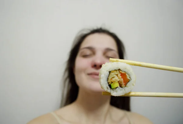 Bella Giovane Donna Mangiare Sushi Con Bacchette Legno Uno Sfondo — Foto Stock