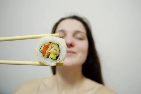 Bella Giovane Donna Mangiare Sushi Con Bacchette Legno Uno Sfondo — Foto Stock
