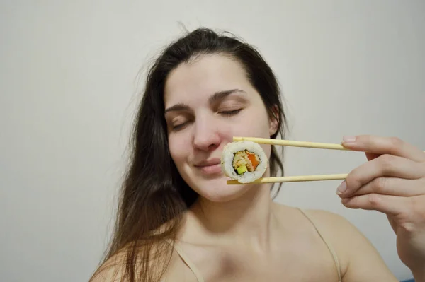 Bella Giovane Donna Mangiare Sushi Con Bacchette Legno Uno Sfondo — Foto Stock