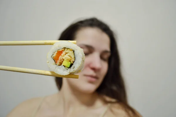 Bella Giovane Donna Mangiare Sushi Con Bacchette Legno Uno Sfondo — Foto Stock